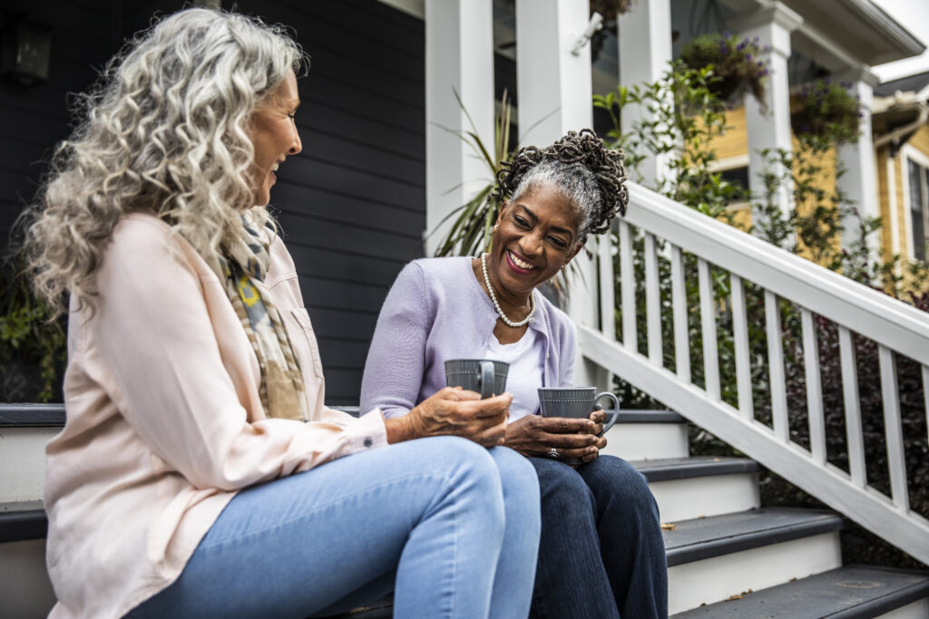 Senior women having coffee in front of suburban home